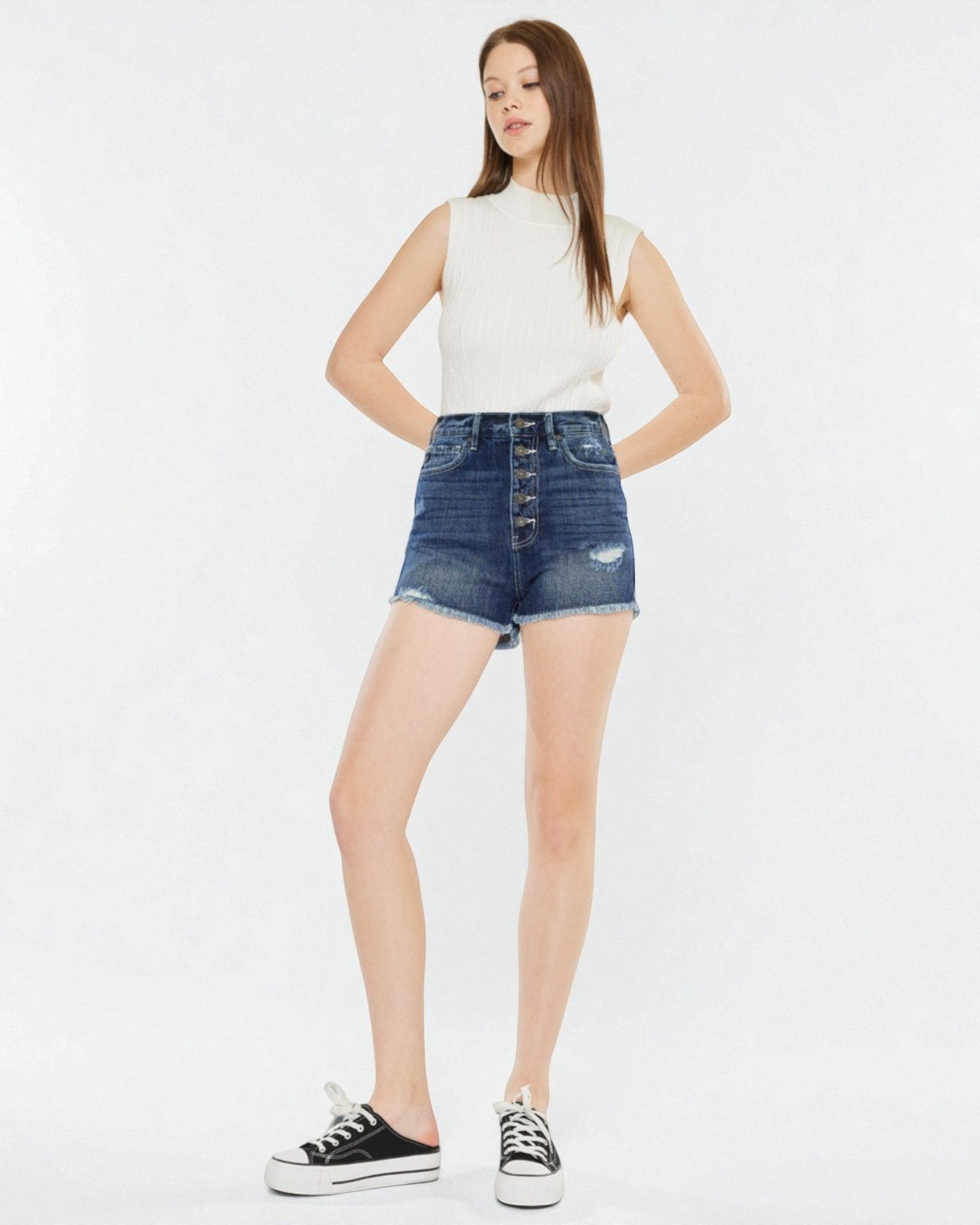 Woman wearing a white sleeveless top and denim skirt on a white background