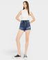 Woman wearing a white sleeveless top and denim shorts on a white background