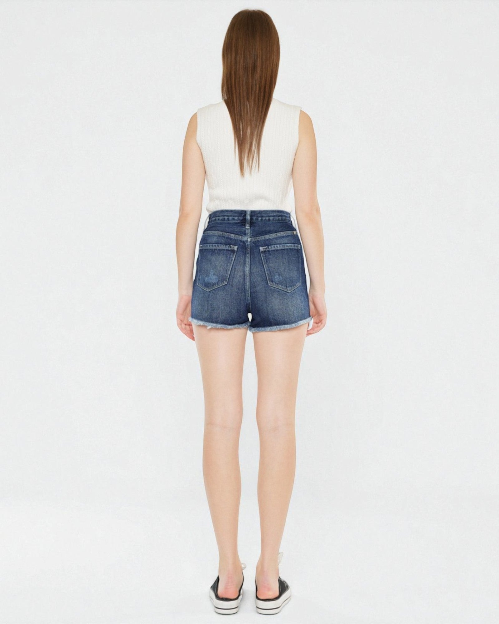 Person wearing a white sleeveless top and blue denim shorts on a white background