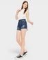 Woman wearing a white sleeveless top and blue denim shorts on a white background