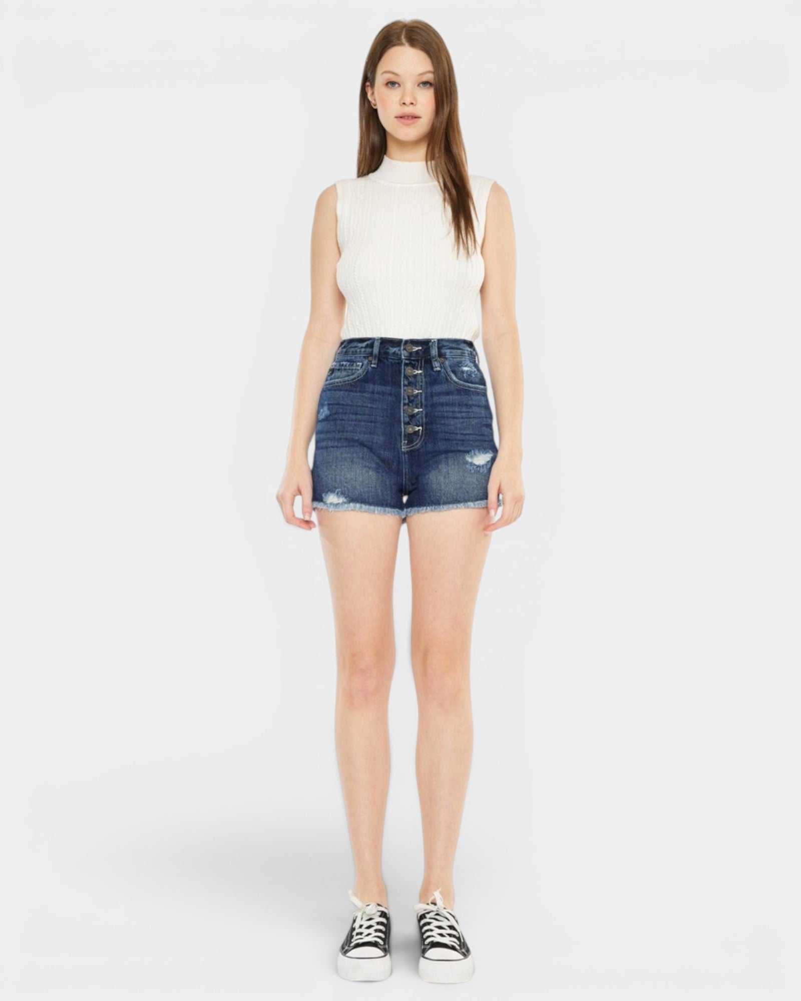 Woman wearing a white sleeveless top and blue denim skirt on a white background