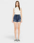 Woman wearing a white sleeveless top and blue denim skirt on a white background