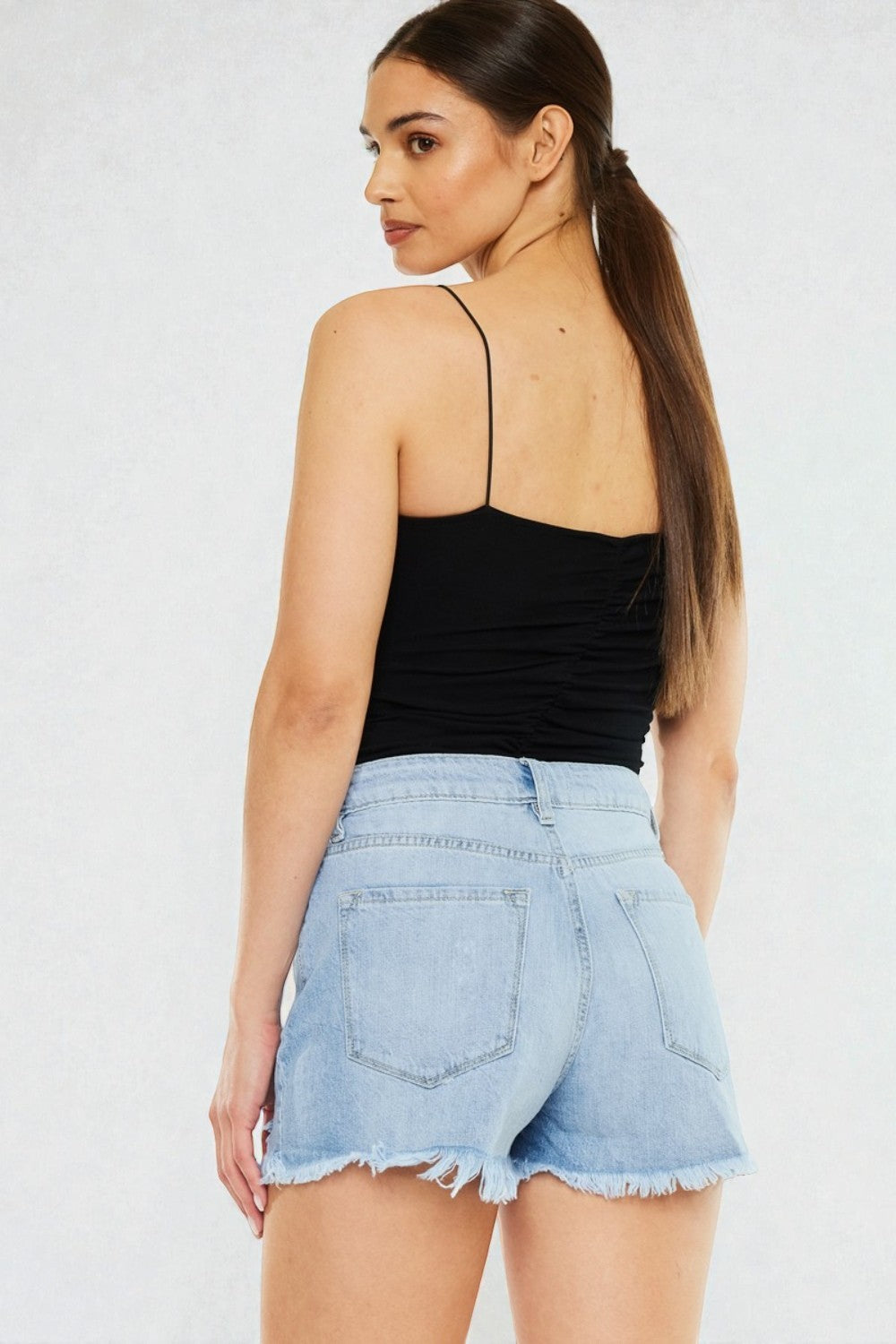 Woman wearing a black top and light blue denim skirt on a white background