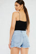 Woman wearing a black top and light blue denim skirt on a white background