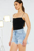 Woman wearing a black top and denim shorts on a white background