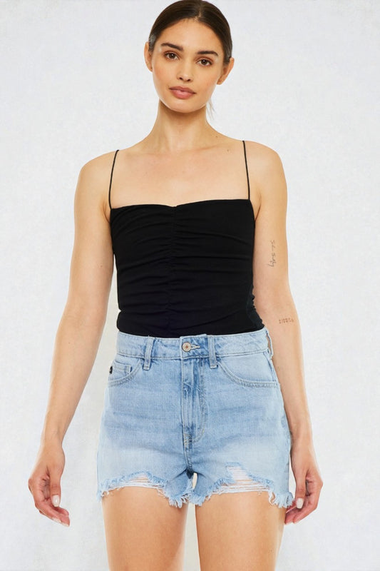 Woman wearing a black strap top and light blue denim shorts on a white background