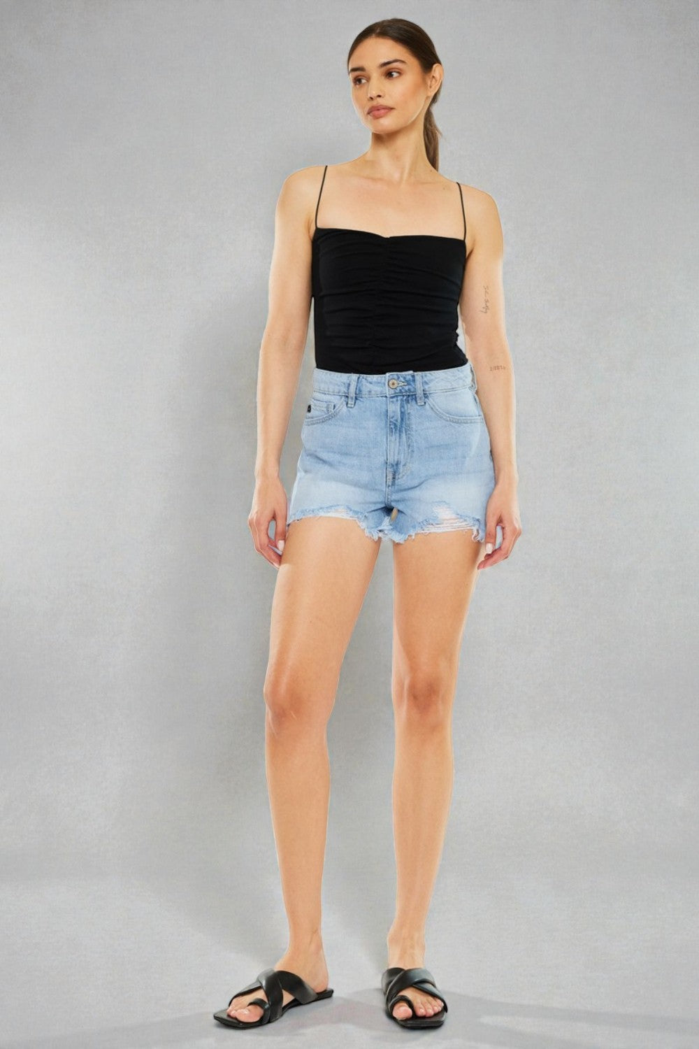 Woman wearing a black strapless top and denim shorts on a gray background