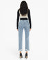 A woman shown from the back wearing light-wash blue cropped jeans with frayed hems, a black long-sleeve top layered over a cream vest, and black high heels against a plain white studio background.