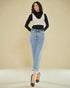 Woman wearing a black and white sweater with a black top and blue jeans on a beige background
