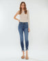 Woman wearing a beige top and blue jeans on a white background