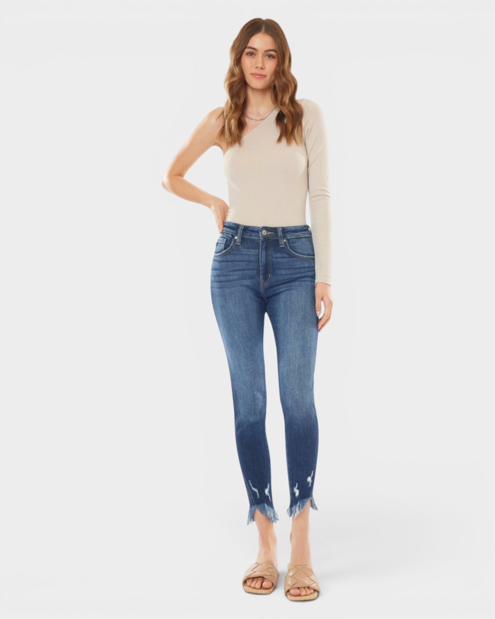 Woman wearing blue jeans and a beige top on a white background