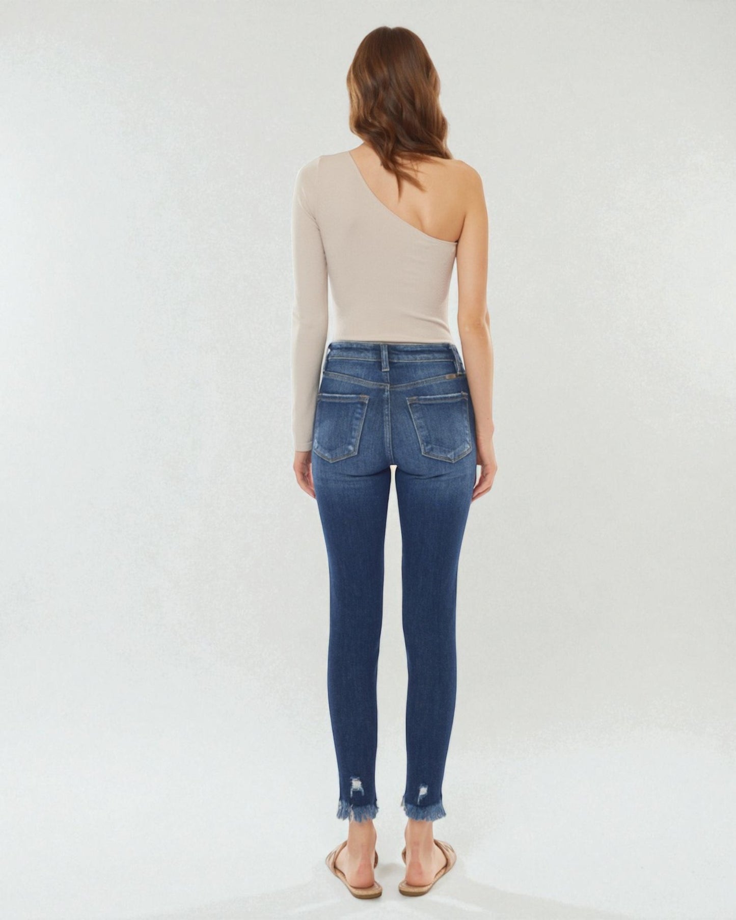 Woman wearing blue jeans and a beige top on a white background