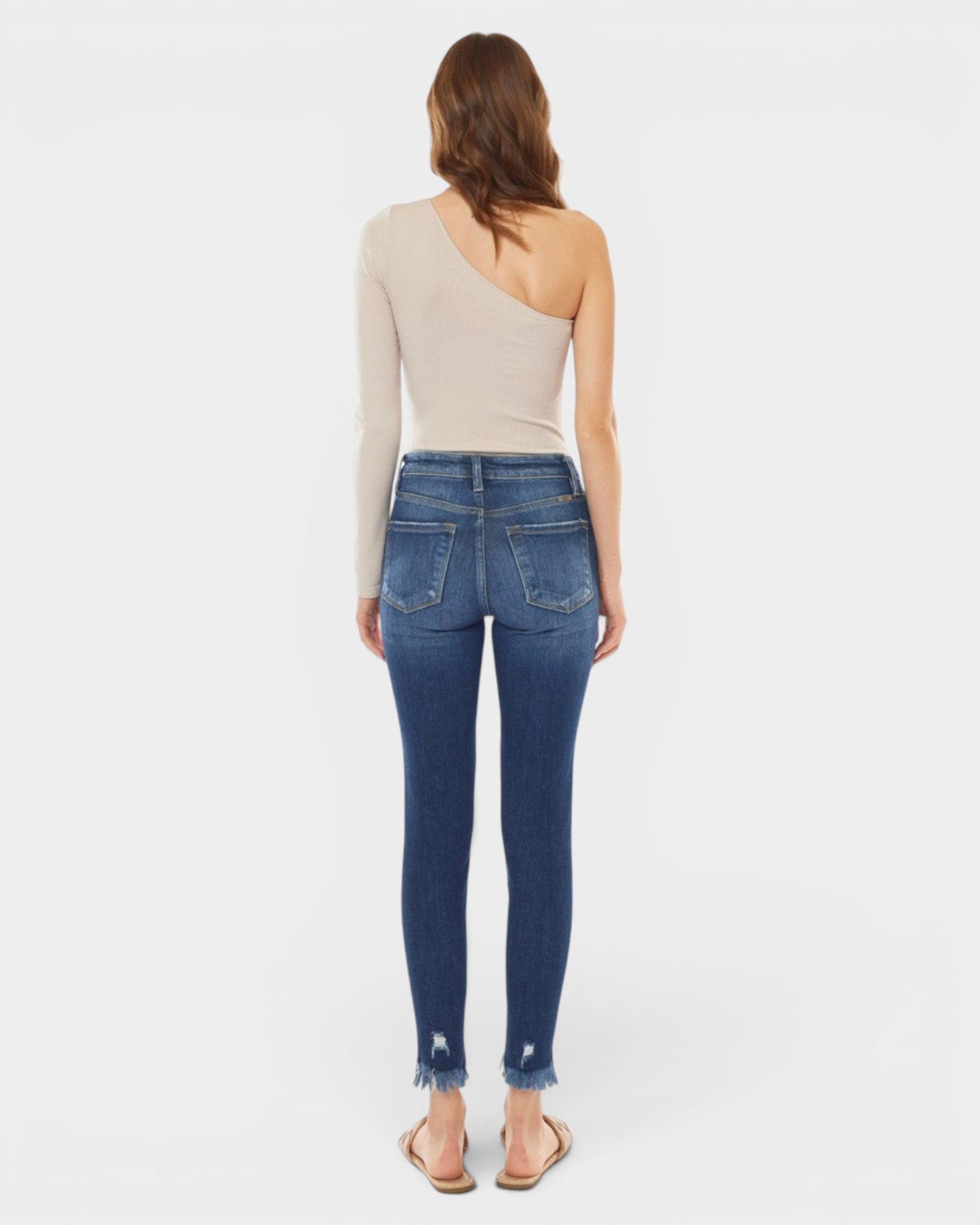 Woman wearing blue jeans and a beige top on a white background