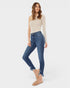 Woman wearing blue jeans and a beige top on a white background