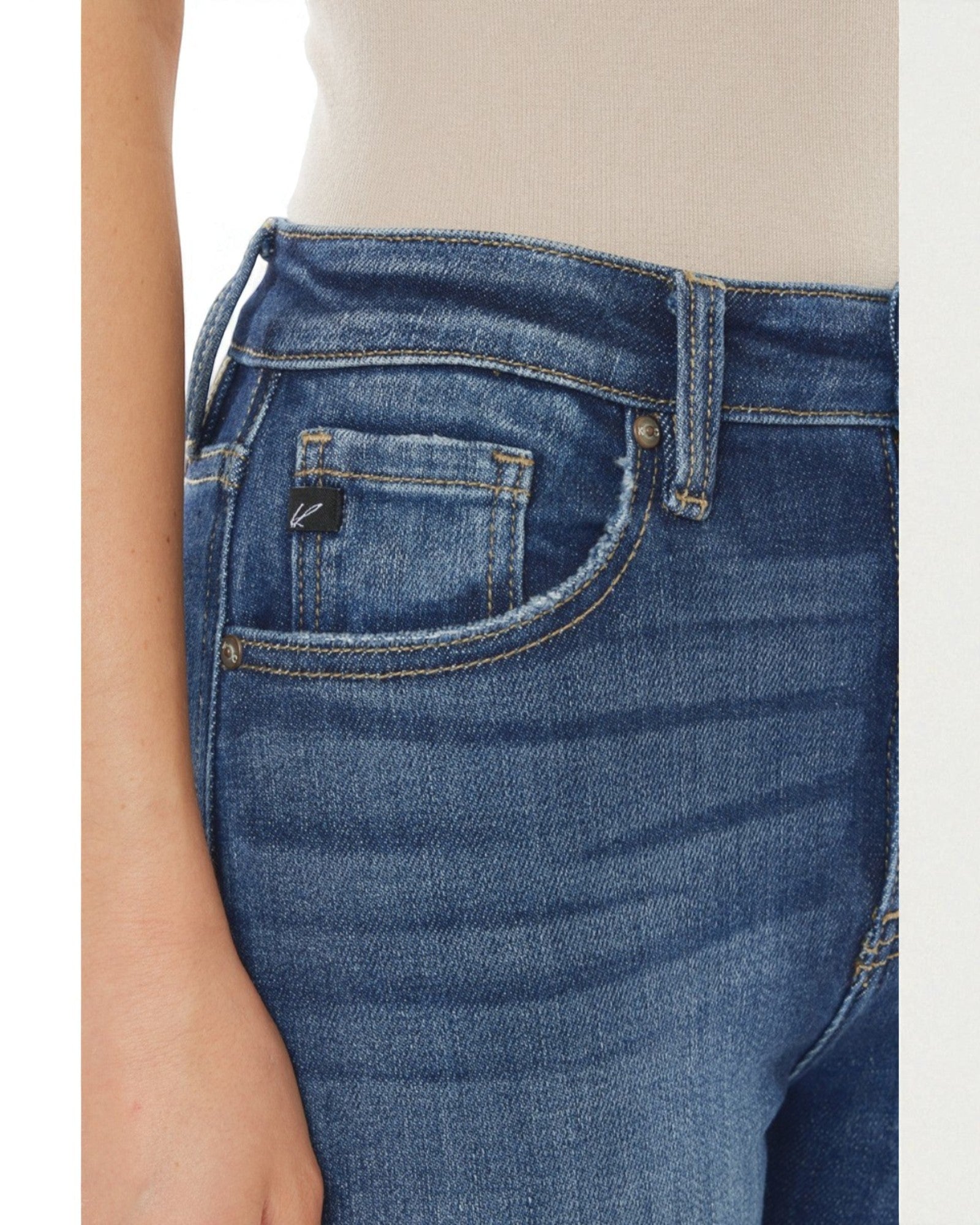 Close-up of blue jeans with a brand logo on the pocket against a neutral background