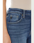Close-up of blue jeans with a brand logo on the pocket against a neutral background