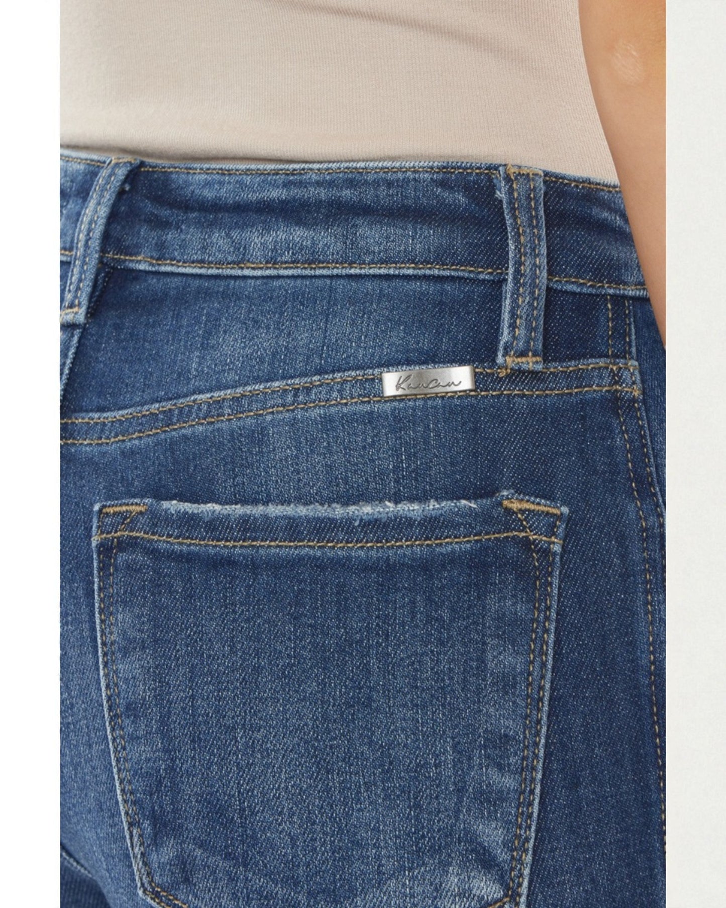 Close-up of blue jeans with a visible brand label on a plain background