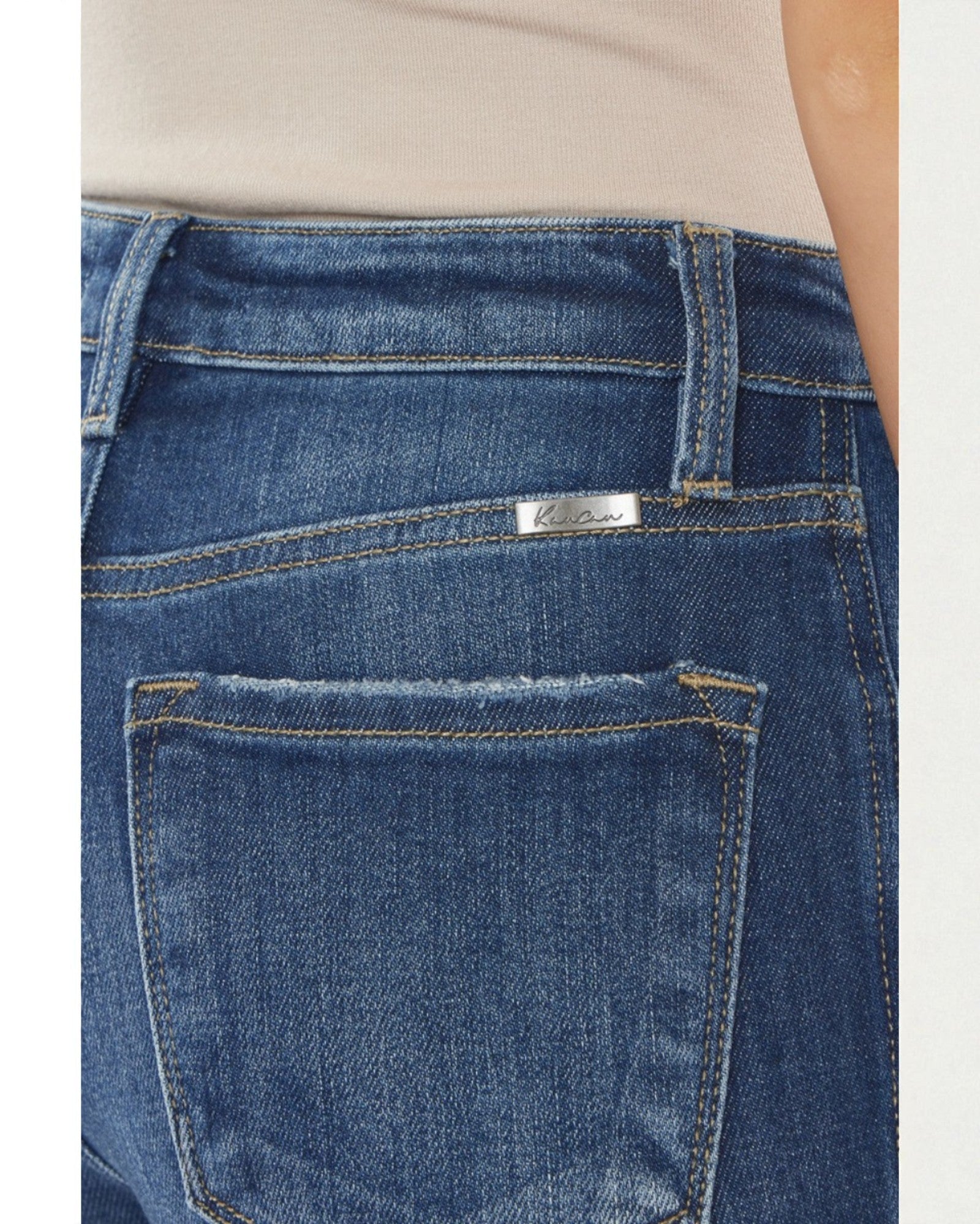 Close-up of blue jeans with a visible brand label on a plain background