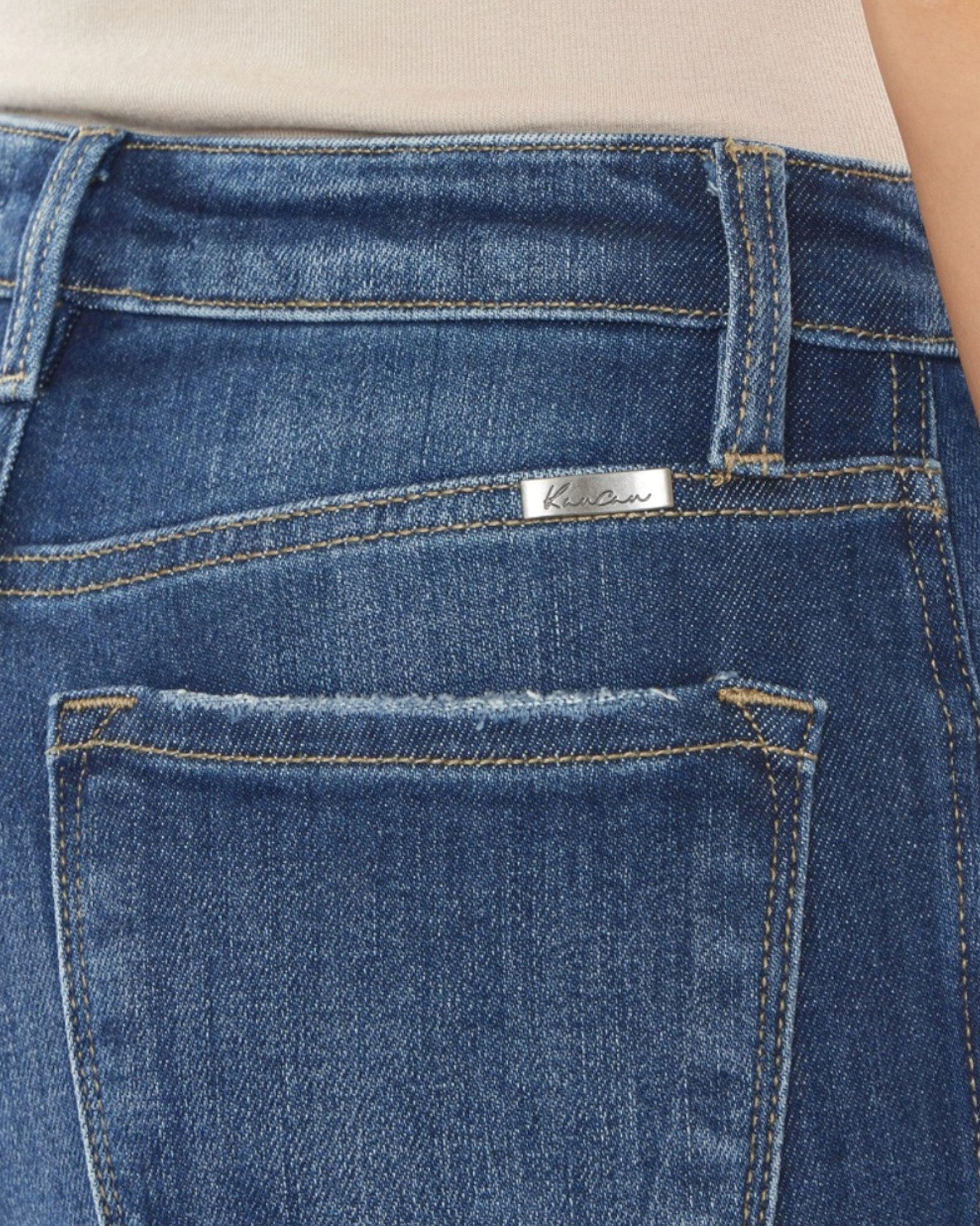 Close-up of blue jeans with a brand label on the back pocket.