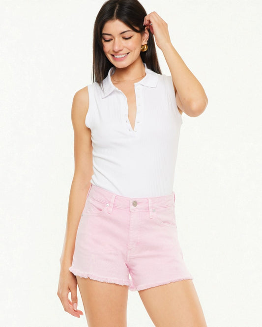 Woman wearing a white sleeveless polo shirt and pink shorts on a white background
