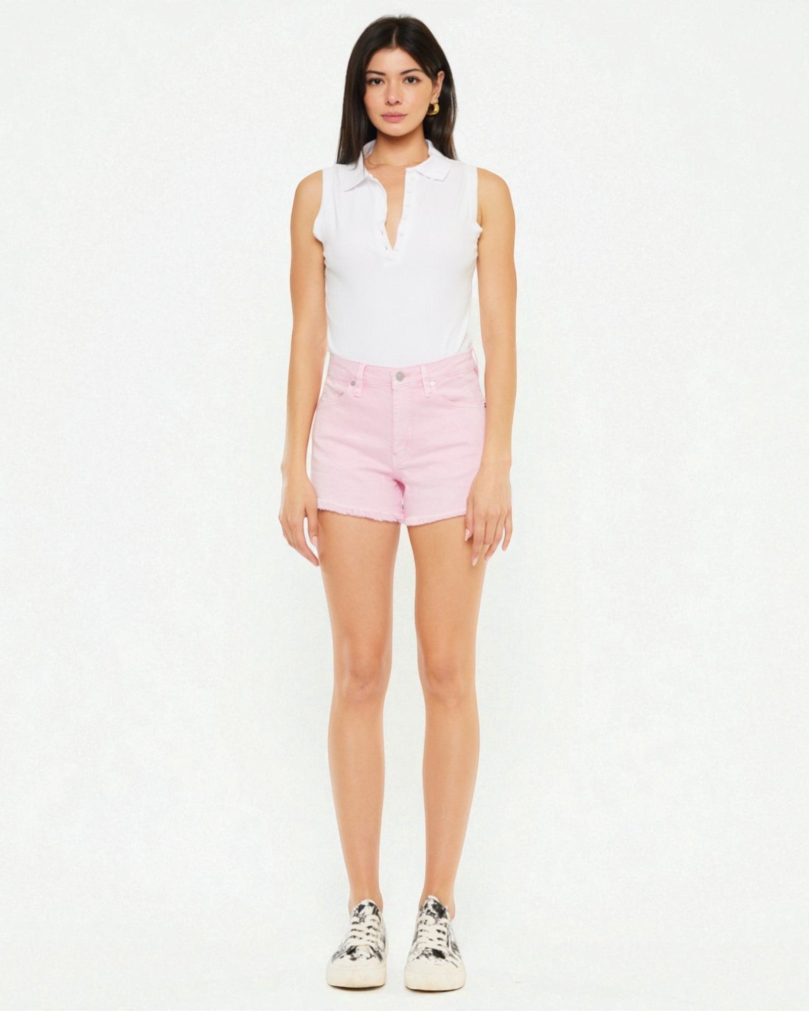 Woman wearing a white sleeveless top and pink shorts on a white background