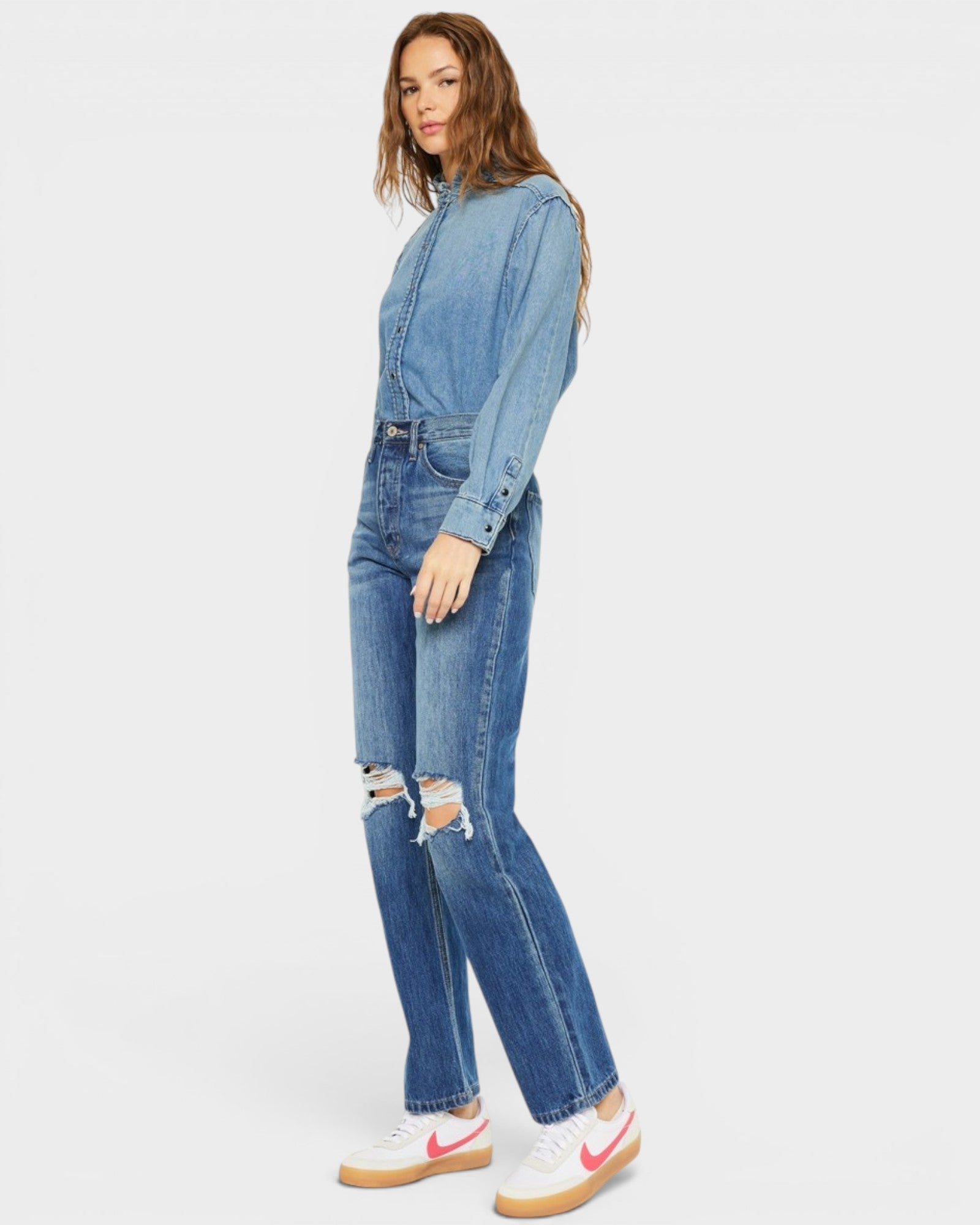Woman wearing a denim jumpsuit on a white background