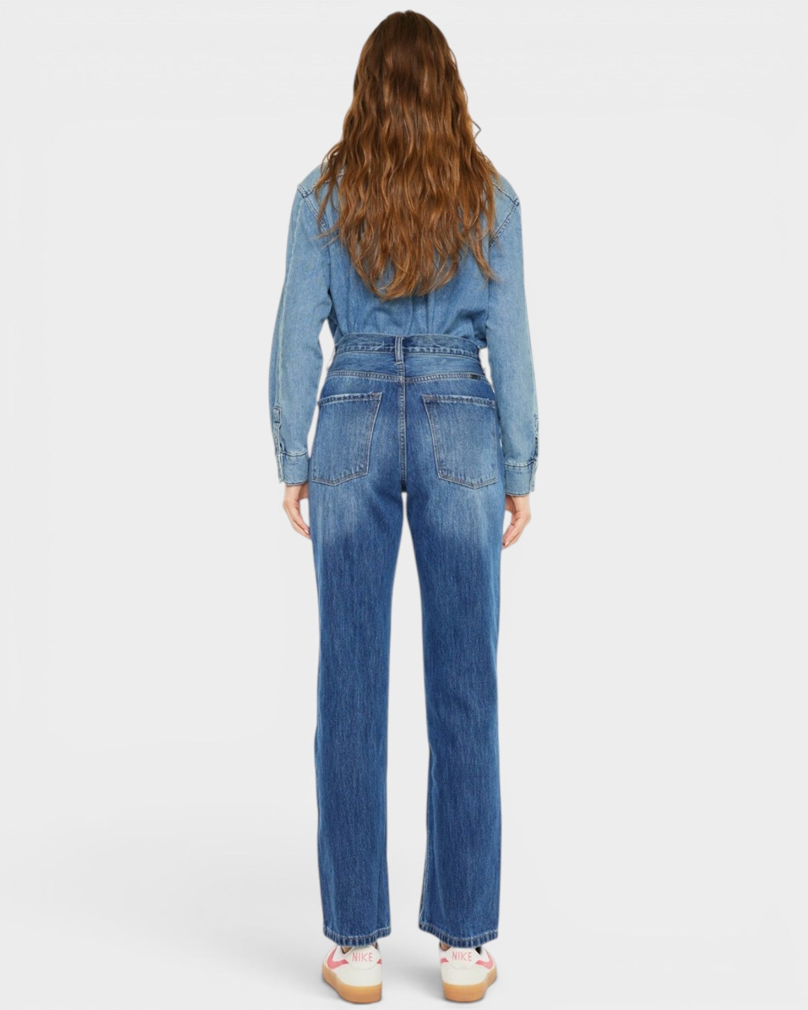Person wearing a blue denim jumpsuit on a white background
