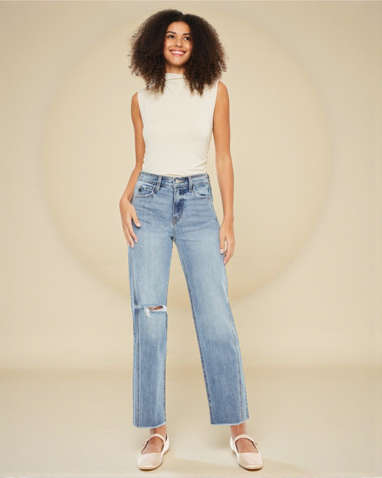 Woman wearing light blue jeans with a white background