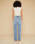 Person wearing light blue jeans and a white top on a beige background