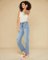 Woman wearing light blue jeans and a white top on a beige background