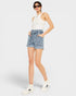 Woman wearing a white sleeveless top and denim shorts on a white background