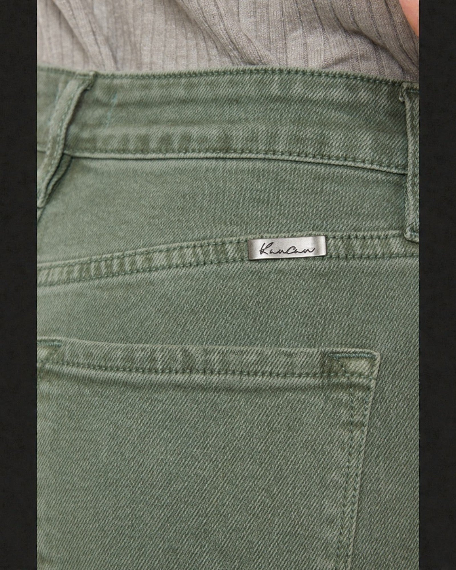 Green pants with a brand label on the pocket against a dark background