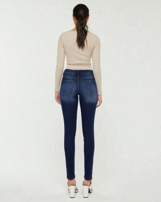 Person wearing blue jeans and a beige top on a white background