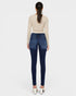 Person wearing blue jeans and a beige top on a white background