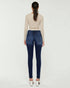 Person wearing blue jeans and a beige top on a white background
