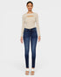 Woman wearing a beige long-sleeve top and blue jeans on a white background