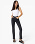 A woman modeling black pinstriped jeans with a white sleeveless top and black sandals, standing against a plain white studio background.