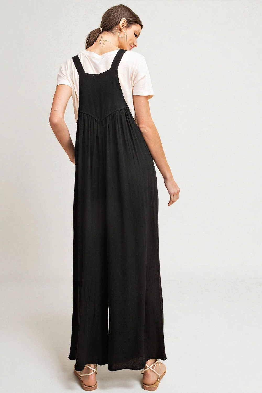 Woman wearing a black dress over a white shirt on a plain background