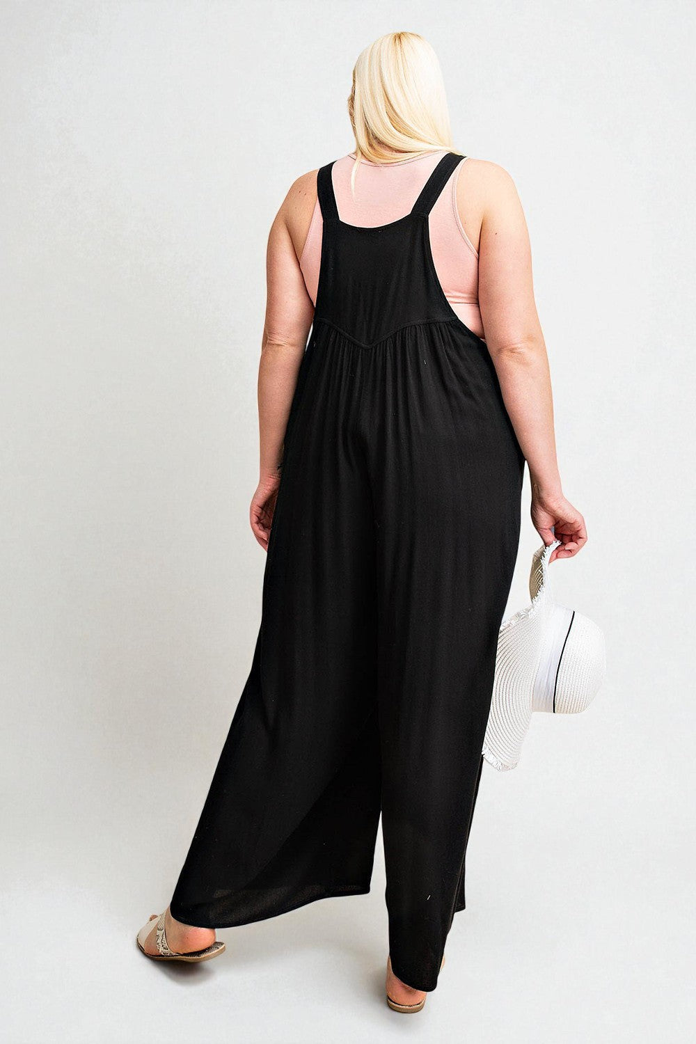 Person wearing a black sleeveless jumpsuit on a white background
