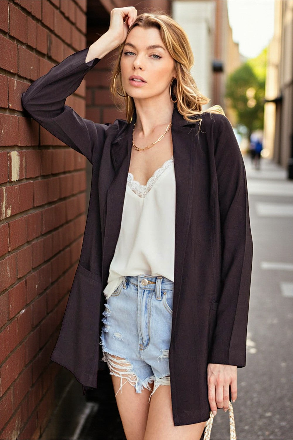 Woman leaning against a brick wall on a street