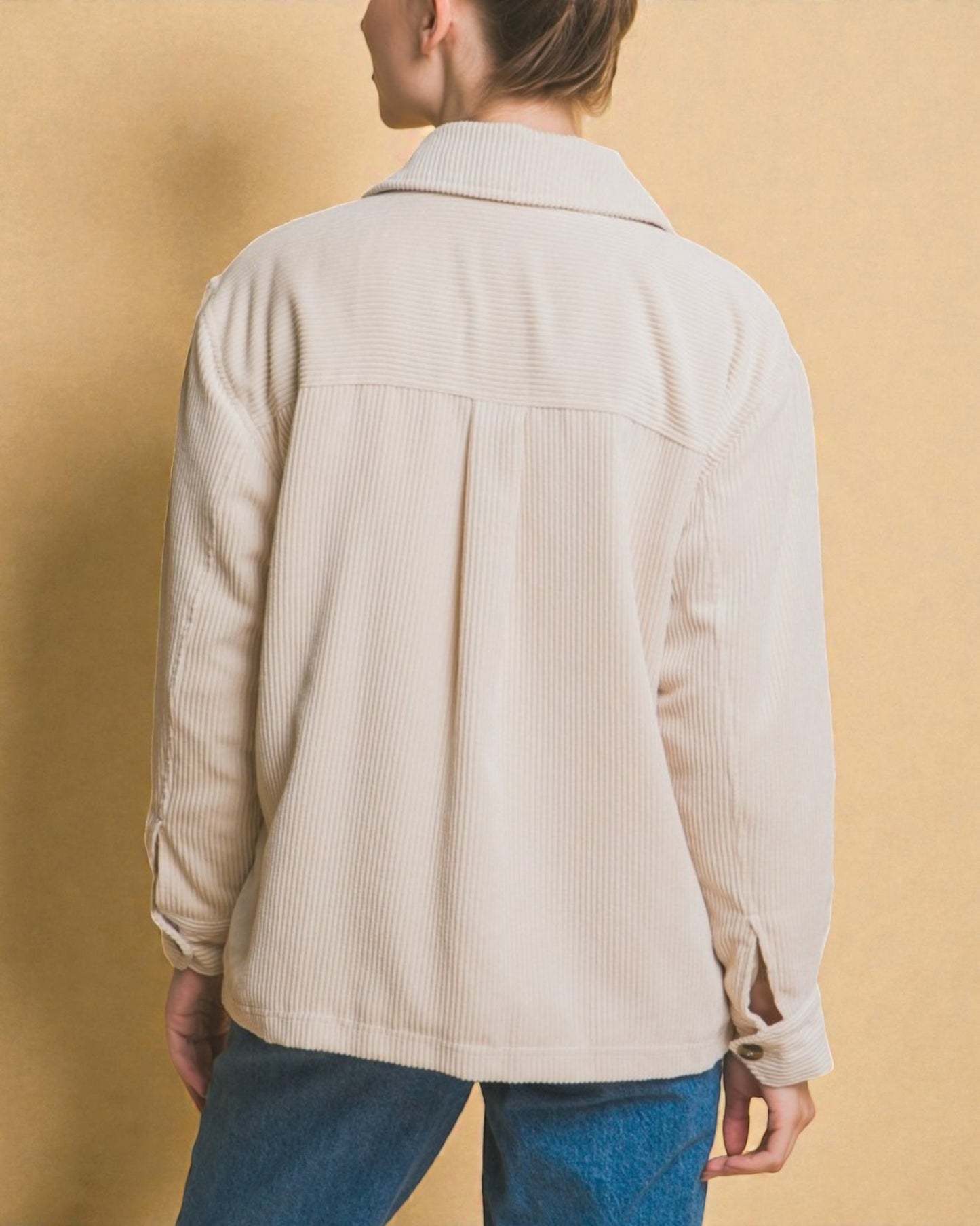 Person wearing a beige corduroy jacket against a beige background