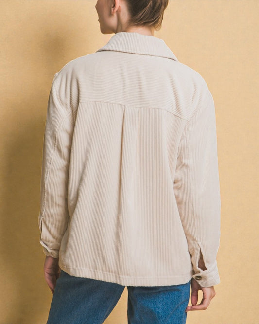 Person wearing a beige corduroy jacket against a beige background