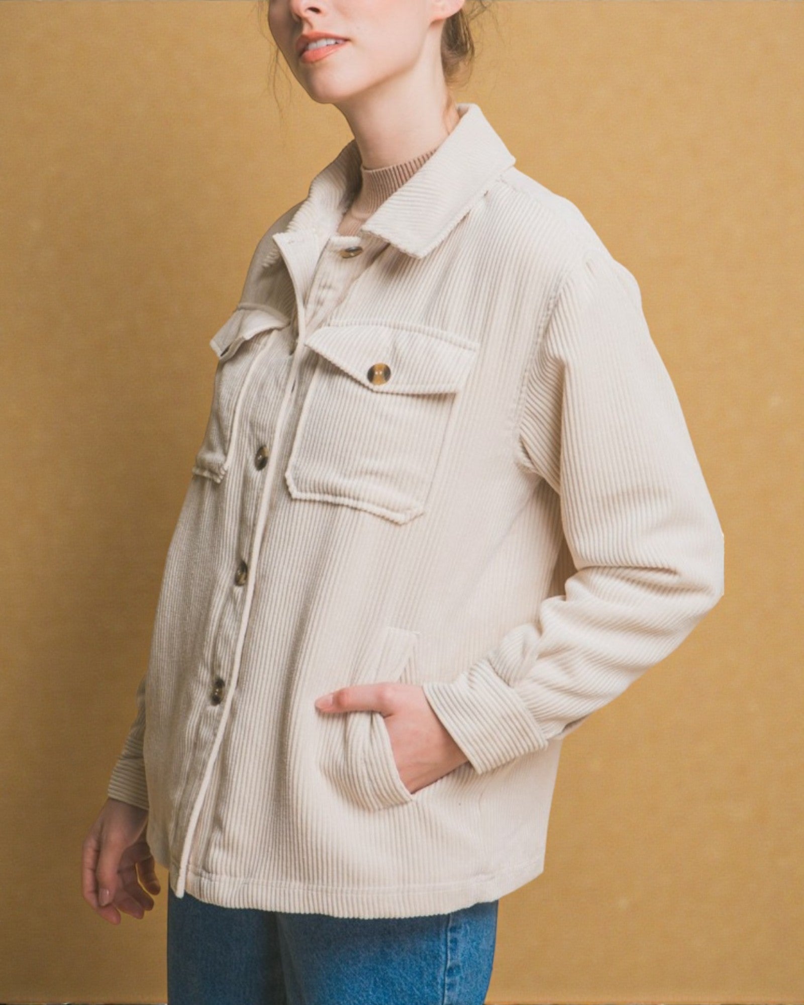 Person wearing a beige corduroy jacket against a mustard yellow background