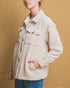 Person wearing a beige corduroy jacket against a mustard yellow background