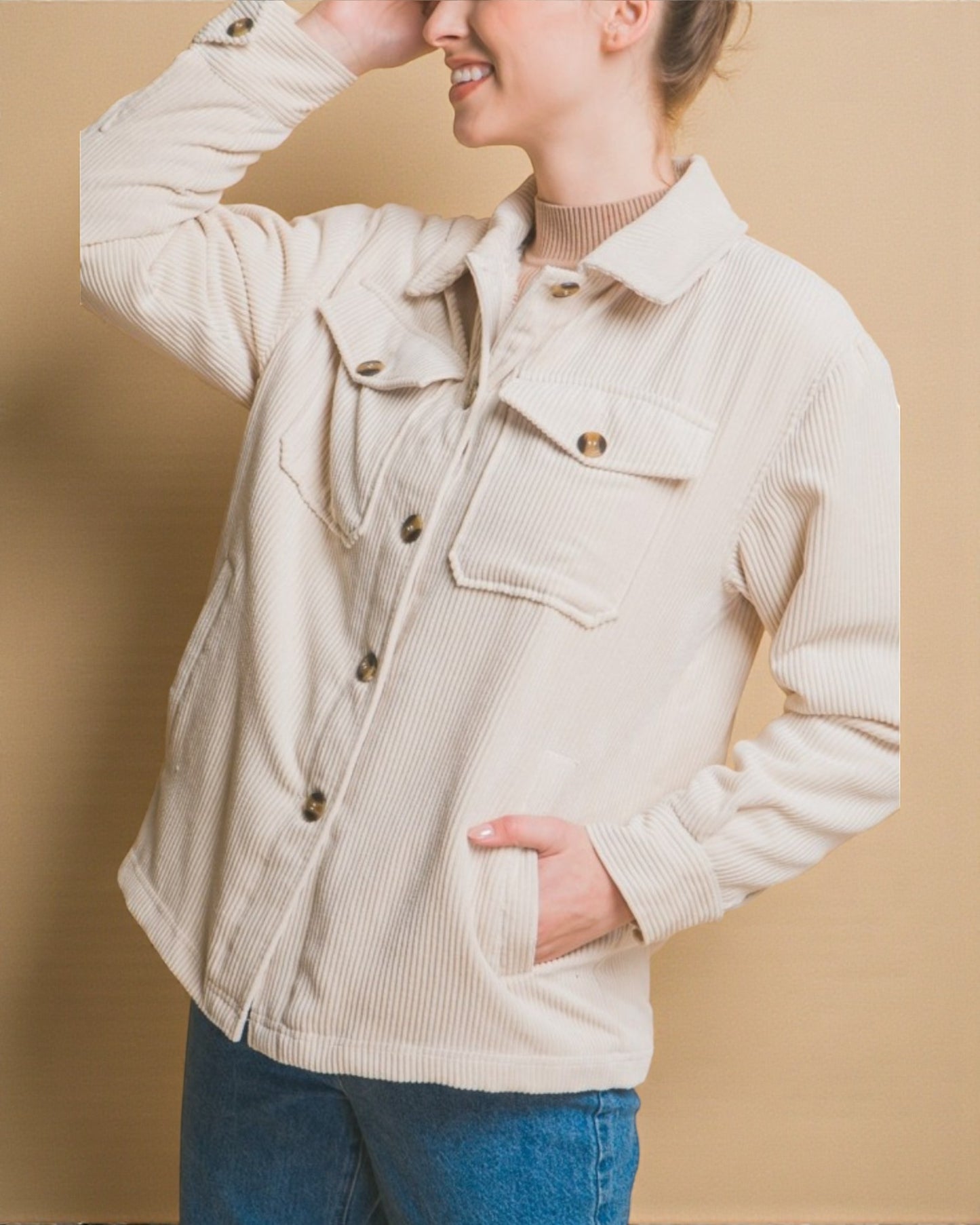Person wearing a beige corduroy jacket against a beige background