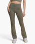 A model wearing high-waisted olive green athletic pants and white sneakers, shown from the waist down against a light gray studio background.