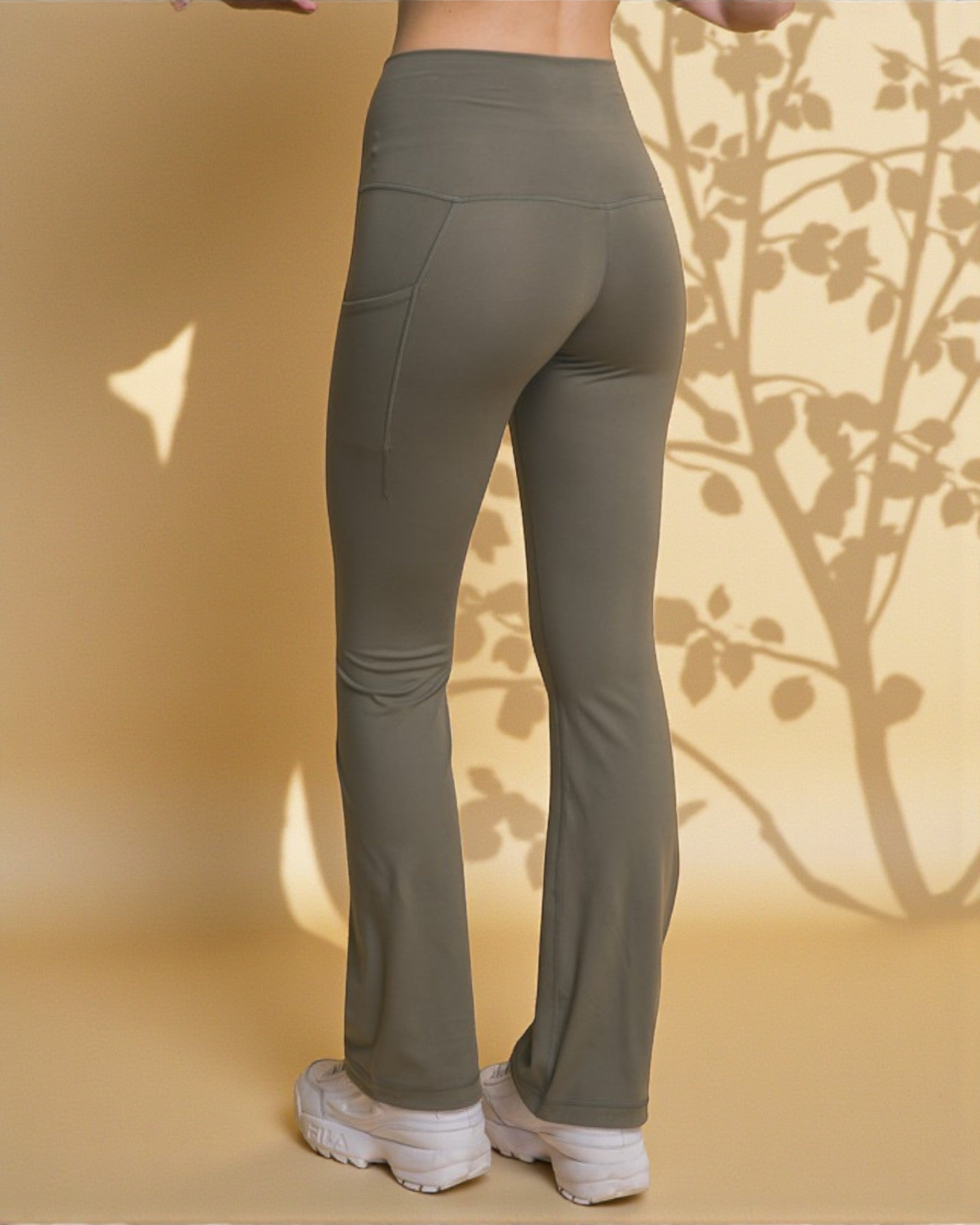 Olive green leggings worn by a person on a beige background