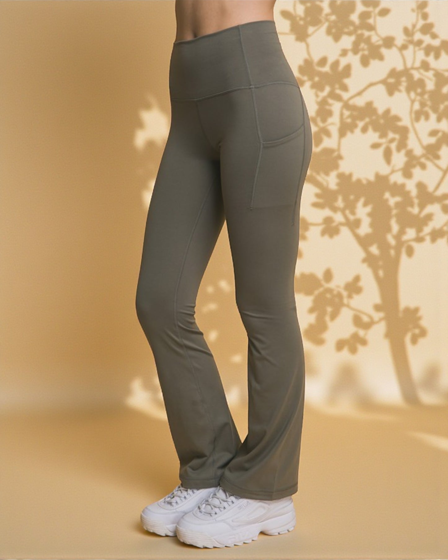 Person wearing olive green pants with a neutral background