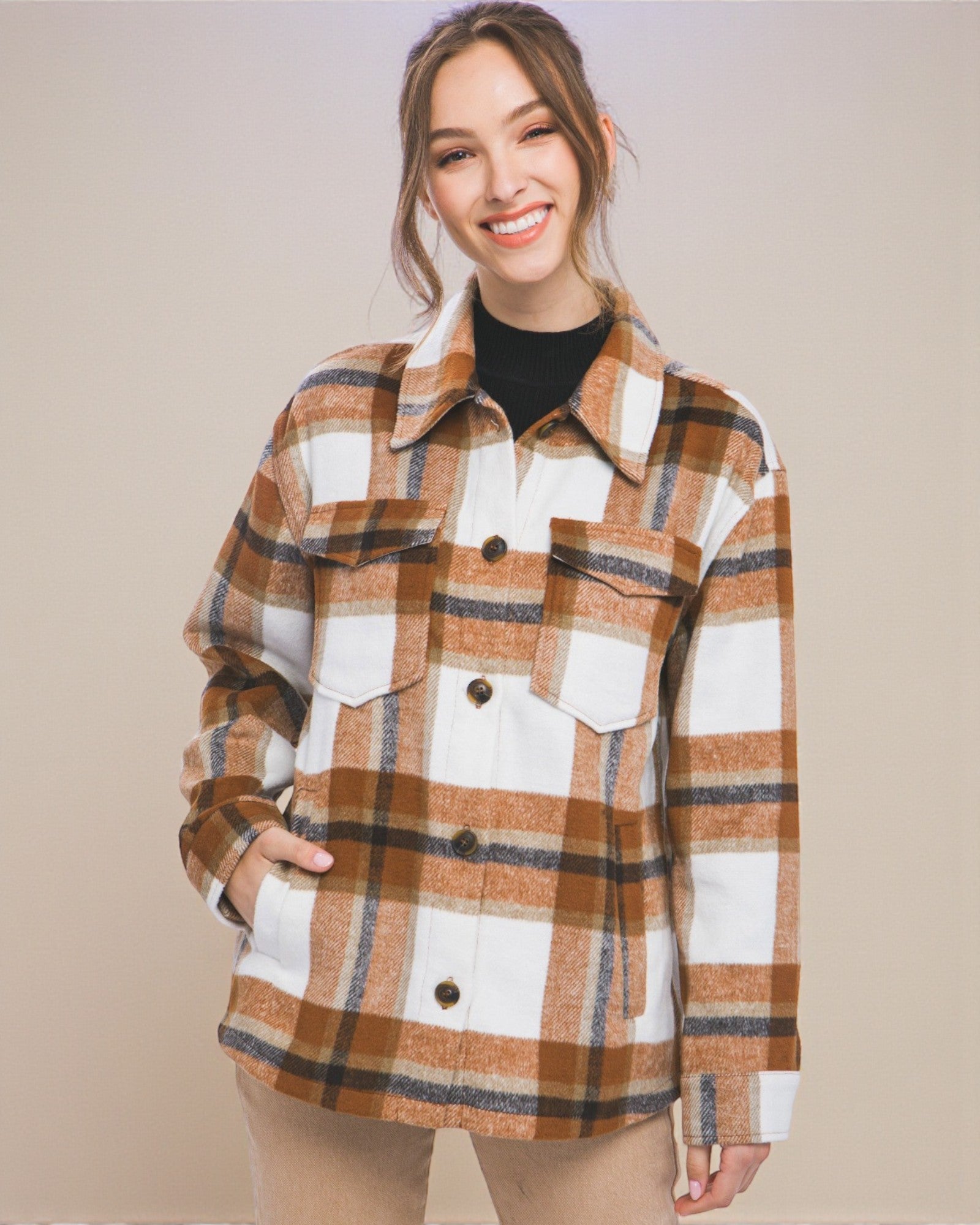Woman wearing a plaid shirt over a black top against a beige background