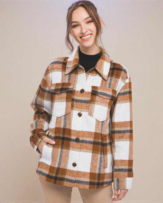 Woman wearing a plaid shirt over a black top against a beige background